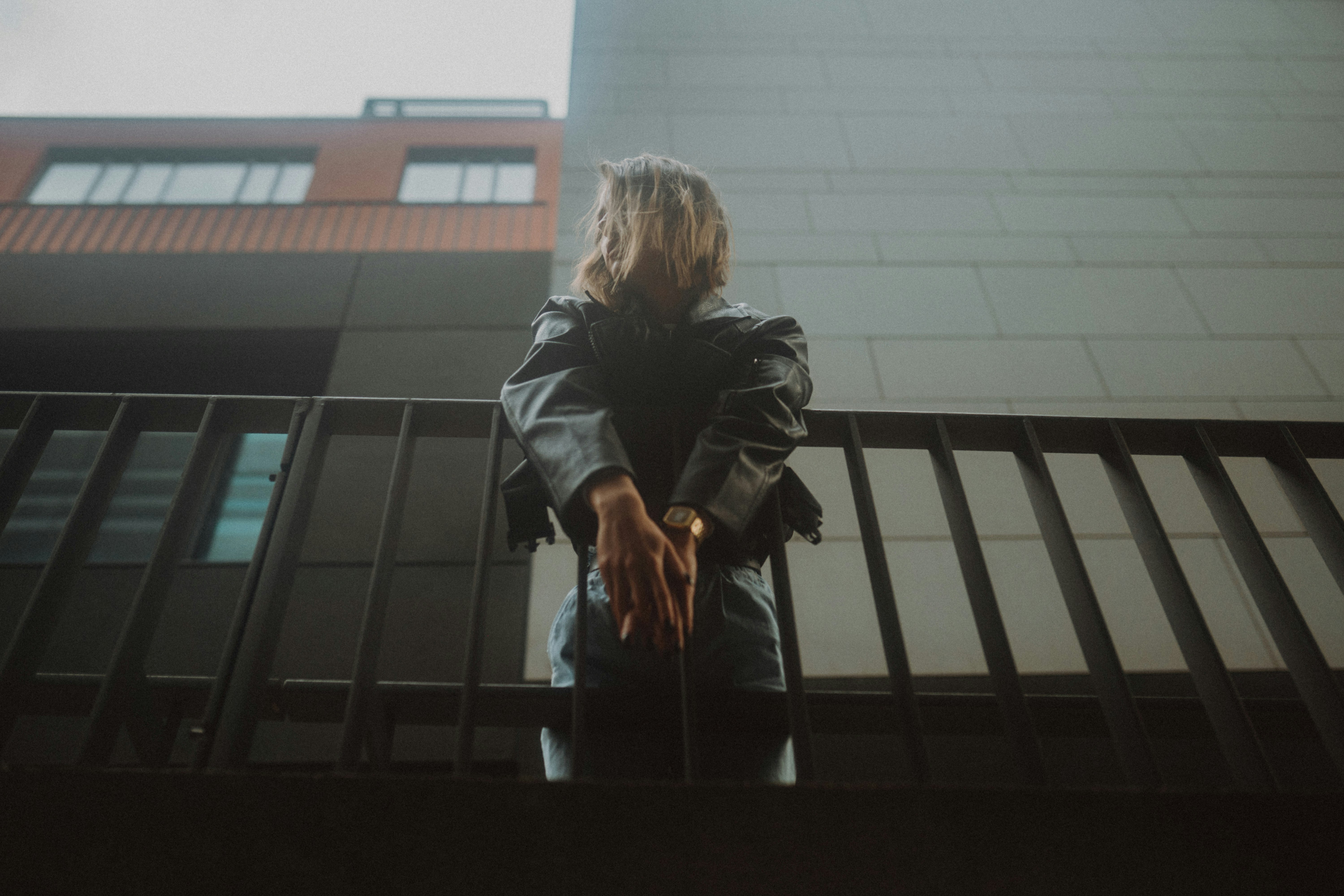 woman in black leather jacket standing beside glass window